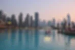 Ein Boot auf türkisfarbenem Wasser, umgeben von den Wolkenkratzern Dubais bei Dämmerung, schafft eine ruhige und zugleich lebendige städtische Szene.